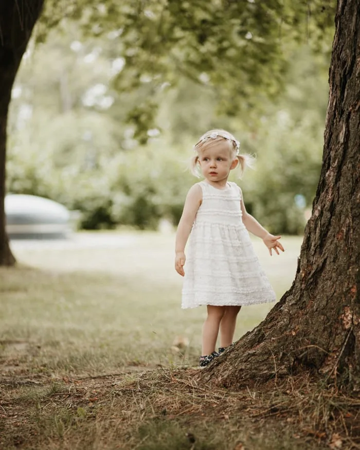 perhekuvaus tyttölapsi seisoo puun vieressä hatanpään arboretumilla